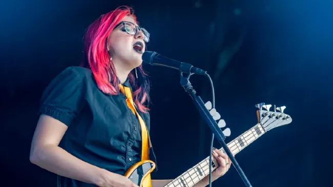 woman singing and playing bass guitar