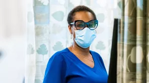 Portrait of nurse Nadia Foureau standing at a computer station in the infusion center at Tufts Medical Center.