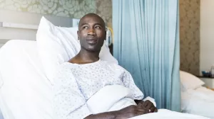 Patient sitting up in hospital bed and looking hopeful and off to the distance.