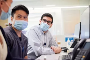 Pharmacy Resident, Dylan Freeman, meeting with Kevin Wu, Clinical Staff Pharmacist, and Erin Greel, Clinical Staff Pharmacist, at a computer station at Lowell General Hospital on D4.