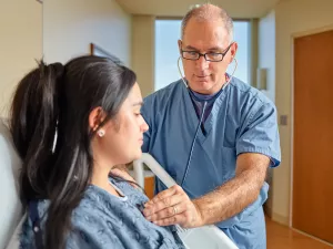 Cardiologist Eric Ewald, MD uses stethoscope to check the heart of a patient in Lowell General Hospital's Heart and Vascular inpatient unit.