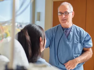 Cardiologist Eric Ewald, MD examines and talks to patient in Lowell General Hospital's Heart and Vascular inpatient unit.