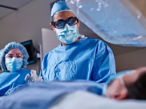 Cardiologist Omar Ali, MD, FACC performing a surgery on a heart and vascular patient in Lowell General Hospital's Cath Lab with the help of a nurse.