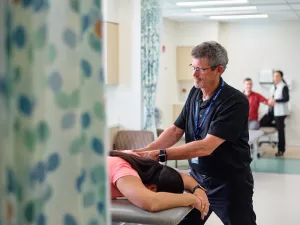 Todd Haynes, Physical Therapist at MelroseWakefield Hospital's 888 Main rehabilitation office, massages shoulder of patient on table. 