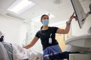 Kim-Yen Vo, Melrose Wakefield Hospital Ultrasound Technologist, pointing at screen while providing an ultrasound to patient.