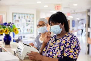 Sonia Henry and Farding Jarbath, both PCTs (Patient Care Techicians) at MelroseWakefield Hospital, making a phone call at the reception desk.