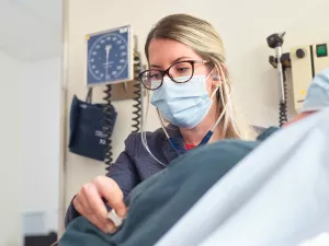 Nurse Practitioner, Natalie Bonvie-Hill, listening to patient's heart with a stethoscope during a cardiovascular appointment at Tufts Medical Center.