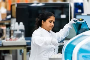 Vijitha Thayaparan, senior medical technologist, lifting a set of tubes into a machine in the laboratory medicine department at Tufts Medical Center.