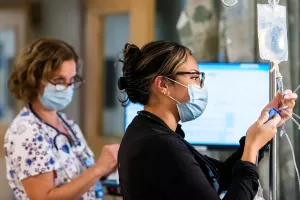 Ellen Babcock, RN teaching Jessica Herrera, RN (coop from a university) how to setup an IV bag and log the information into computer system in the surgical unit at Tufts Medical Center.