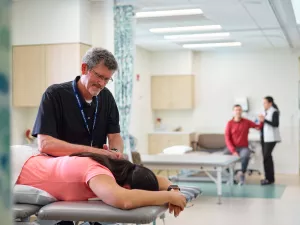 Todd Haynes, Physical Therapist at MelroseWakefield Hospital's 888 Main rehabilitation office, massages shoulder of patient on table. 