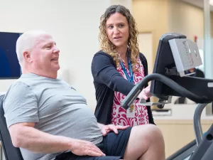 MelroseWakefield Hospital's Tracy Rochester, Physical Therapist at 888 Main showing patient how to use elliptical machine. 