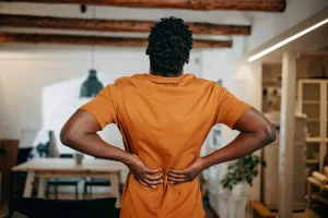 Patient holding and stretching back at home and suffering from pain.