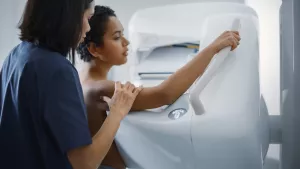 Technician preps a breast health patient for a mammography scan by adjusting arms. 