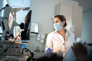 Doctor examining patient with endoscope and reviewing information on computer screen.