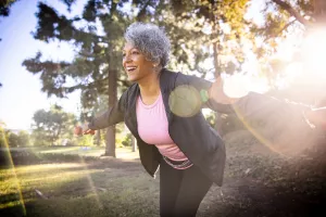 Smiling senior lifting weights outdoor in a park.