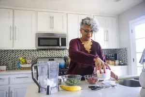 Weight loss patient applying their meal replacement and planning knowledge in the kitchen by making a nutritious smoothie.