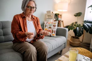 Senior sitting on couch at home and squeezing hands.