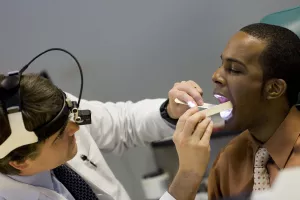 Otolaryngologist Richard Wein, MD examining patient's throat during an ENT appointment at Tufts Medical Center.