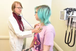 Gastroenterologist Harmony Allison, MD uses a stethoscope to examine patient in a clinic appointment.