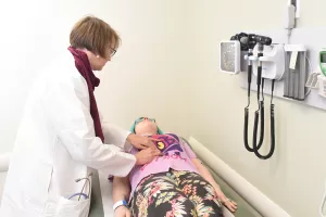 Gastroenterologist Harmony Allison, MD examines a patient's stomach with pressure from hands in a clinic appointment at Tufts Medical Center.