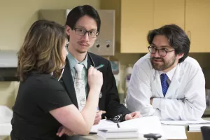 Lester Leung, MD (Director, Comprehensive Stroke Center; Director, Stroke and Young Adults (SAYA) Program), Cara Clifford, MA CCC-SLP (speech language pathologist) and Ali Daneshmand, MD (Neurology senior resident) discussing a case in the Neuro Trauma Unit at Tufts Medical Center.