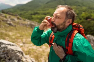 Allergy patient holding chest and suffering from shortness of breathe and an asthma attack while hiking.