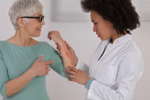 Allergy doctor looking at a patient's hives and rash during an appointment.