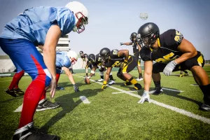 Two football teams line up during a scrimmage at a high school stadium field.