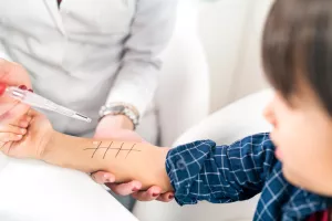 Doctor performing an allergy skin prick test on child during a clinic appointment.