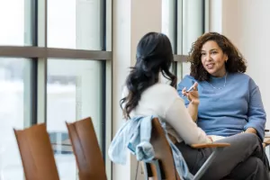 Patient listens to counselor during a clinic appointment while sitting next to large windows.