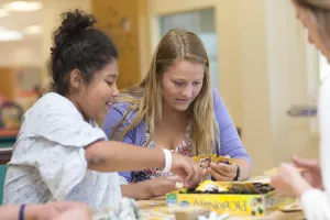 Child Life Specialist plays games with a patient in a hospital gown at Tufts Medical Center's Ace's Place.