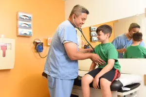 Khoa Tran, MD examines patient's stomach with a stethoscope in the Pediatric Gastroenterology clinic at Tufts Medical Center.