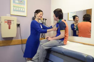 Shirley Huang, MD examines patient with a stethoscope during a pediatric primary care appointment at Tufts Medical Center.