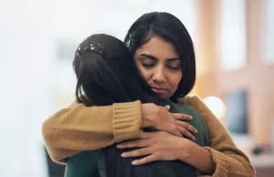 A friend embracing another with a hug during a time of grieving.