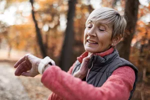 Jogger stopping to check pulse and read results on their smartwatch on an Autumn day.