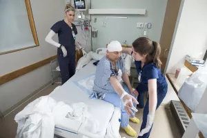 Physical therapist Sarah Krasney and student work with recovering stroke patient after neurosurgery in trauma unit.