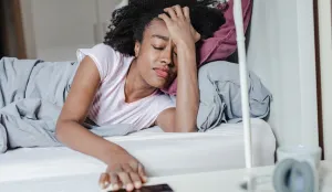 Woman, in bed, distressed from lack of sleep.