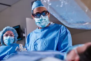 Cardiologist Omar Ali, MD, FACC performing a surgery on a heart and vascular patient in Lowell General Hospital's Cath Lab with the help of a nurse.