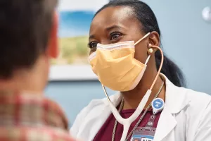 Maggie Pierre, NP checking patient's heart with a stethoscope during a primary care appointment at MelroseWakefield Hospital's 888 Main office.