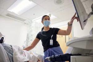 Kim-Yen Vo, Melrose Wakefield Hospital Ultrasound Technologist, pointing at screen while providing an ultrasound to patient.