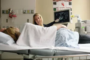 A Tufts Medical Center echocardiogram technologist explains the screen to Hypertrophic Cardiomyopathy Center (HCM) patient.