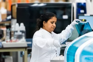 Vijitha Thayaparan, senior medical technologist, lifting a set of tubes into a machine in the laboratory medicine department at Tufts Medical Center.