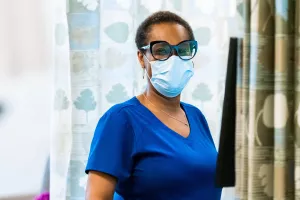 Portrait of nurse Nadia Foureau standing at a computer station in the infusion center at Tufts Medical Center.