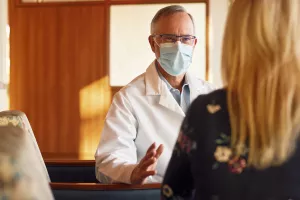 Greg Schumaker, MD (Medical Director at Lowell General Hospital's ICU, Section Chief of Critical Care, Adult Sleep Medicine) talking to a family member in the waiting room of the Intensive Care Unit (ICU).