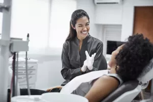 Happy dentist putting gloves on with patient before a dental exam in a clinic appointment.