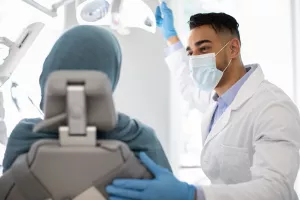 Dentist preparing a patient for a dental exam at a clinic appointment.