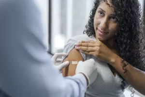 Doctor placing a bandage on a patient after receiving a vaccine at the Travelers Health Clinic.