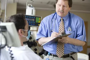 Ray Comenzo, MD (Director of Blood Bank, Transfusion and Stem Cell Services at Tufts Medical Center) examining patient during an appointment with aphoresis equipment.