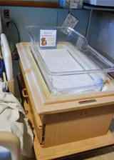 A baby basinet next to a bed A baby basinet next to a bed