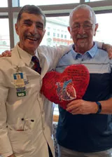 Pat holding his heart pillow with his physician after transplant Pat holding his heart pillow with his physician after transplant